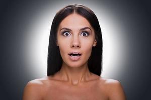 No way Portrait of surprised young shirtless woman looking at camera and keeping mouth open while standing against grey background photo