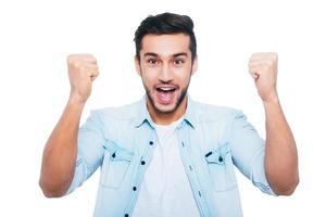 I won Happy young Indian man gesturing and smiling while standing against white background photo