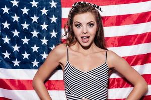 Hello from USA Beautiful young woman standing against American national flag photo