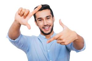 concéntrate en mí alegre joven indio haciendo gestos con el dedo y sonriendo mientras está de pie contra el fondo blanco foto