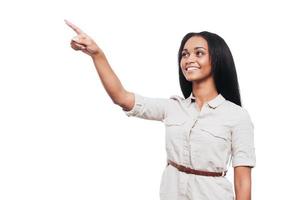 Look at that Beautiful young African woman pointing away and smiling while standing against white background photo