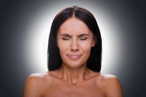 Failed again Portrait of frustrated young shirtless woman keeping eyes closed while standing against grey background photo