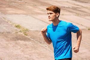 Enjoying his daily jog. Side view of handsome young man running along the road and smiling photo