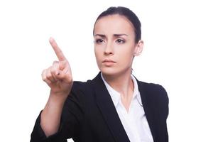 Touching a transparent wipe board. Confident young woman in formalwear touching a transparent wipe board while standing isolated on white photo