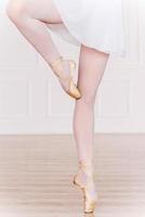 En pointe. Close-up of ballerina legs in white tutu and slippers photo