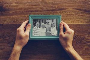 I love my family Close-up top view of man holding photograph of his family over wooden desk photo