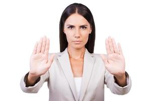 Stop it Confident young businesswoman in suit stretching out hands and showing her palms while standing against white background photo