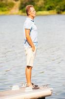 Finding a peaceful place. Side view of thoughtful mature man looking away while standing at the quayside photo