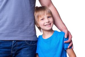 Feeling safe and protected. Father and son standing close to each other while child looking at camera and smiling photo