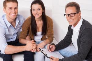 Family therapy . Top view of happy young couple and confident psychiatrist sitting together and smiling photo