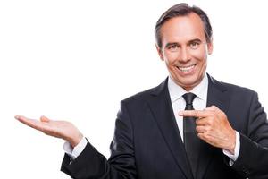 Advertising your product. Happy mature man in formalwear holding copy space on his hand and pointing it while standing isolated on white background photo