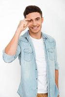 That was as close Cheerful young man gesturing and smiling while standing against white background photo