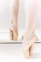 En pointe. Close-up of ballerina legs in slippers standing against mirror photo