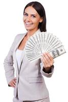 Rich and successful. Happy young businesswoman in suit showing money and smiling while standing against white background photo