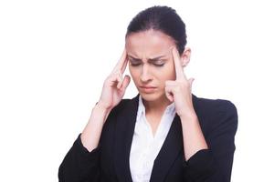 Feeling headache. Frustrated young woman in formalwear touching head with fingers and keeping eyes closed while standing isolated on white photo