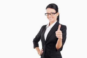 Good job Cheerful young business woman looking at camera and holding her thumb up while standing isolated on white photo
