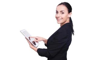 examinando su tableta nueva. vista trasera de una joven confiada en ropa formal que trabaja en una tableta digital y mira por encima del hombro mientras está aislada en blanco
