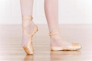 En pointe. Close-up of ballerina legs in white tutu and slippers photo