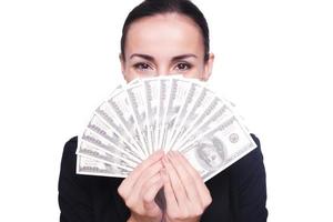 Rich and successful. Happy young woman in formalwear holding paper currency in her hands and looking out of them while standing isolated on white photo