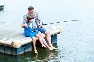 Casting off together. Top view of father and son fishing together on quayside photo