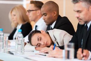 Sleeping at the conference. Tired businesswoman sleeping while sitting at the table with her colleagues photo