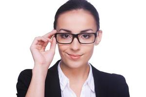 Confident and successful. Confident young woman in formalwear adjusting her eyeglasses and looking at camera while standing isolated on white photo