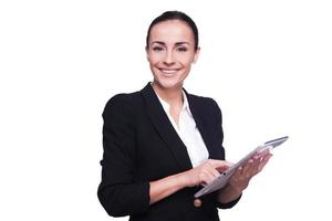 Businesswoman with digital tablet. Confident young woman in formalwear working on digital tablet and smiling while standing isolated on white photo