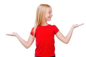 Hard choice. Cute little girl holding copy spaces in hands while standing isolated on white photo