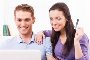 Online shopping. Beautiful young loving couple shopping online while sitting on the couch together photo