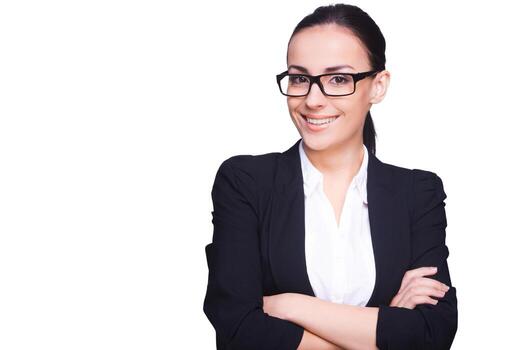 empresaria joven y exitosa. mujer joven confiada en ropa formal y anteojos con los brazos cruzados y sonriendo mientras está de pie aislada en blanco foto