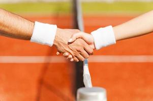 estrechando la mano después de un buen juego. primer plano, de, hombre y mujer, en, pulsera, dar la mano, en, el, red de tenis foto