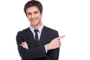 Businessman pointing copy space. Happy young businessman looking at camera and smiling while pointing copy space photo