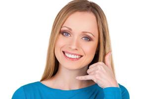 Waiting for your call Beautiful young smiling woman looking at camera and gesturing while standing isolated on white photo