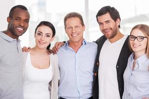 We are strong creative team Group of cheerful business people in casual wear standing close to each other and looking at camera photo