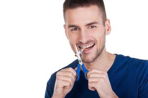 I quit smoking Cheerful young man holding scissors near the cigarette while standing isolated on white background photo