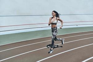 dispuesto a superar cualquier obstáculo. toda la longitud de una mujer joven con ropa deportiva trotando mientras hace ejercicio al aire libre foto