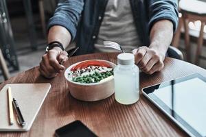 Close-up of man holding fork and table knife while sitting in the cafeteria photo