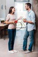 Coffee break. Full length of two cheerful young people talking and smiling during a coffee break in office photo