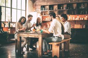 Enjoying dinner with best friends. Group of cheerful young people enjoying dinner while sitting on the kitchen together photo