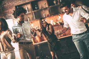 Party every day. Cheerful young people dancing and drinking while enjoying home party on the kitchen photo