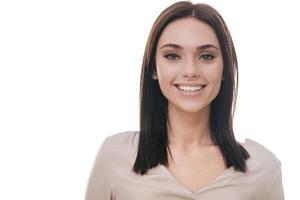 alegre belleza. retrato de una joven atractiva con ropa informal inteligente mirando a la cámara y sonriendo mientras se enfrenta a un fondo blanco foto