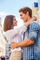 Loving couple. Low angle view of beautiful young loving couple hugging and looking at each other while standing outdoors photo