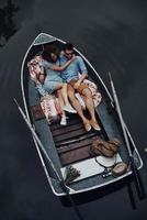 Living at the moment. Top view of beautiful young couple embracing while lying in the boat photo