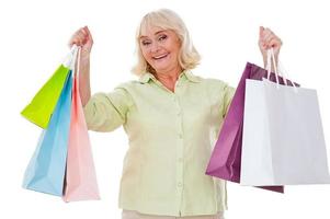 I love shopping Happy senior woman stretching out hands with shopping bags and smiling while standing isolated on white background photo