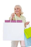 Shopping is my hobby Happy senior woman stretching out hand with shopping bags and smiling while standing isolated on white background photo