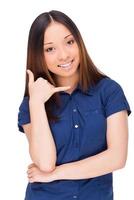 Call me Attractive young Asian woman looking at camera and gesturing while standing isolated on white photo