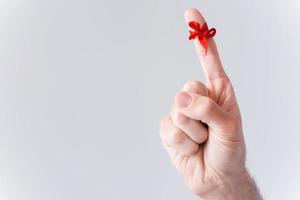 Reminder.  Close-up of male finger with tied with red ribbon and isolated on white photo