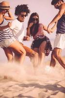 Beach ball. Group of cheerful young people playing with soccer ball on the beach with sea in the background photo