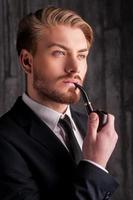Smoking a pipe. Portrait of handsome young man in formalwear smoking a pipe and looking away photo