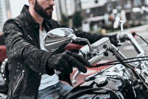 Feeling the freedom. Close up of young man sitting on the motorbike while spending time outdoors photo